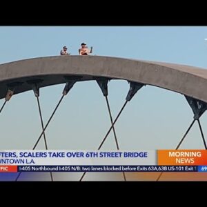 Spectators scale 6th Street Bridge to watch cars drift, do burnouts