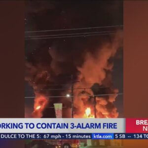 Massive fire burns through roof of building in Paramount