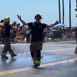 Fire hose cools people down during fiesta parade